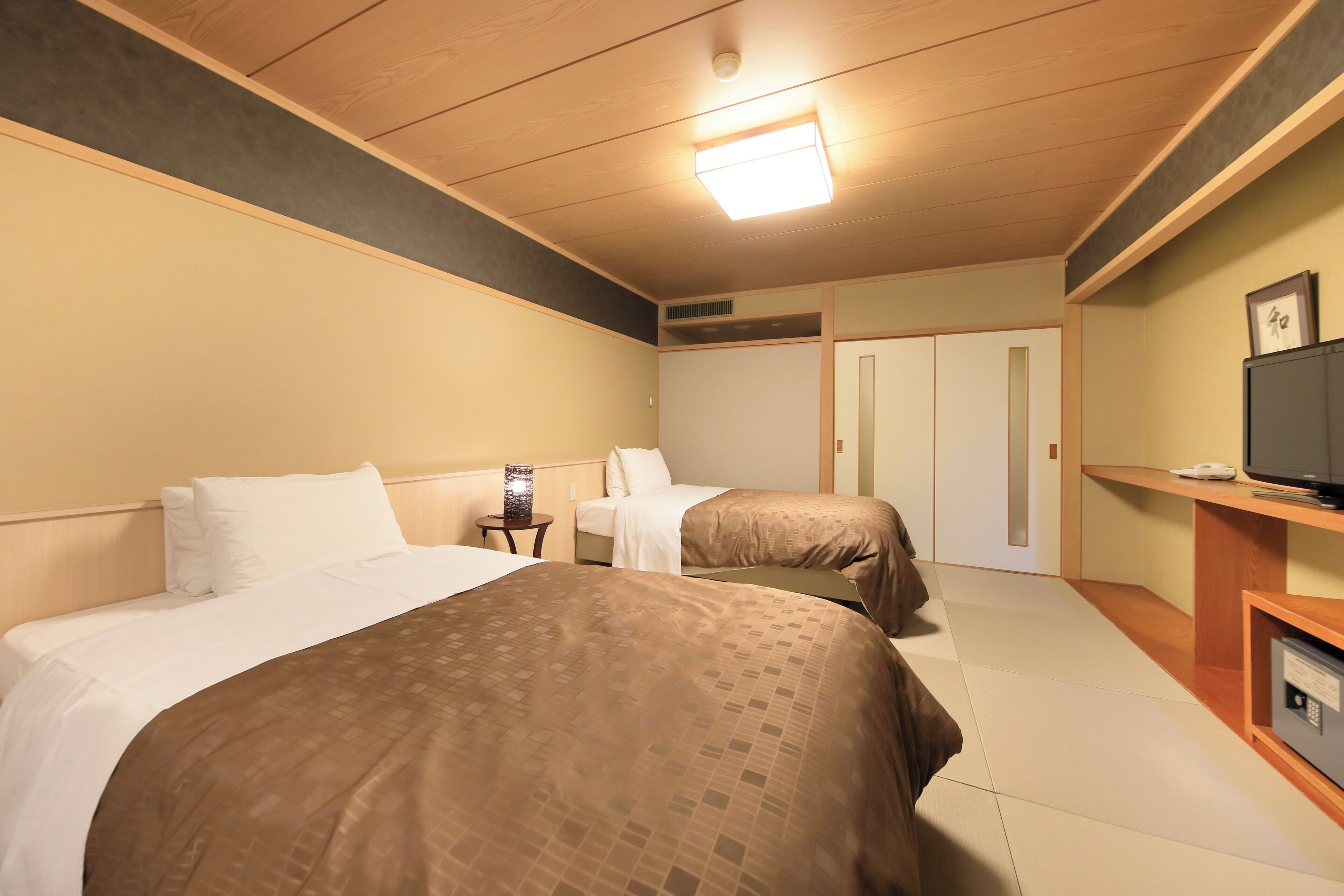 Habitación de hotel con dos camas, televisión, una mesita y un armario.