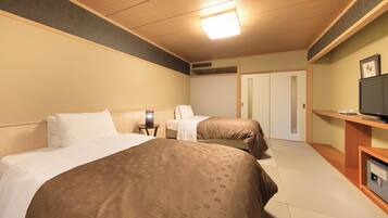 Habitación de hotel con dos camas, televisión, una mesita y un armario.