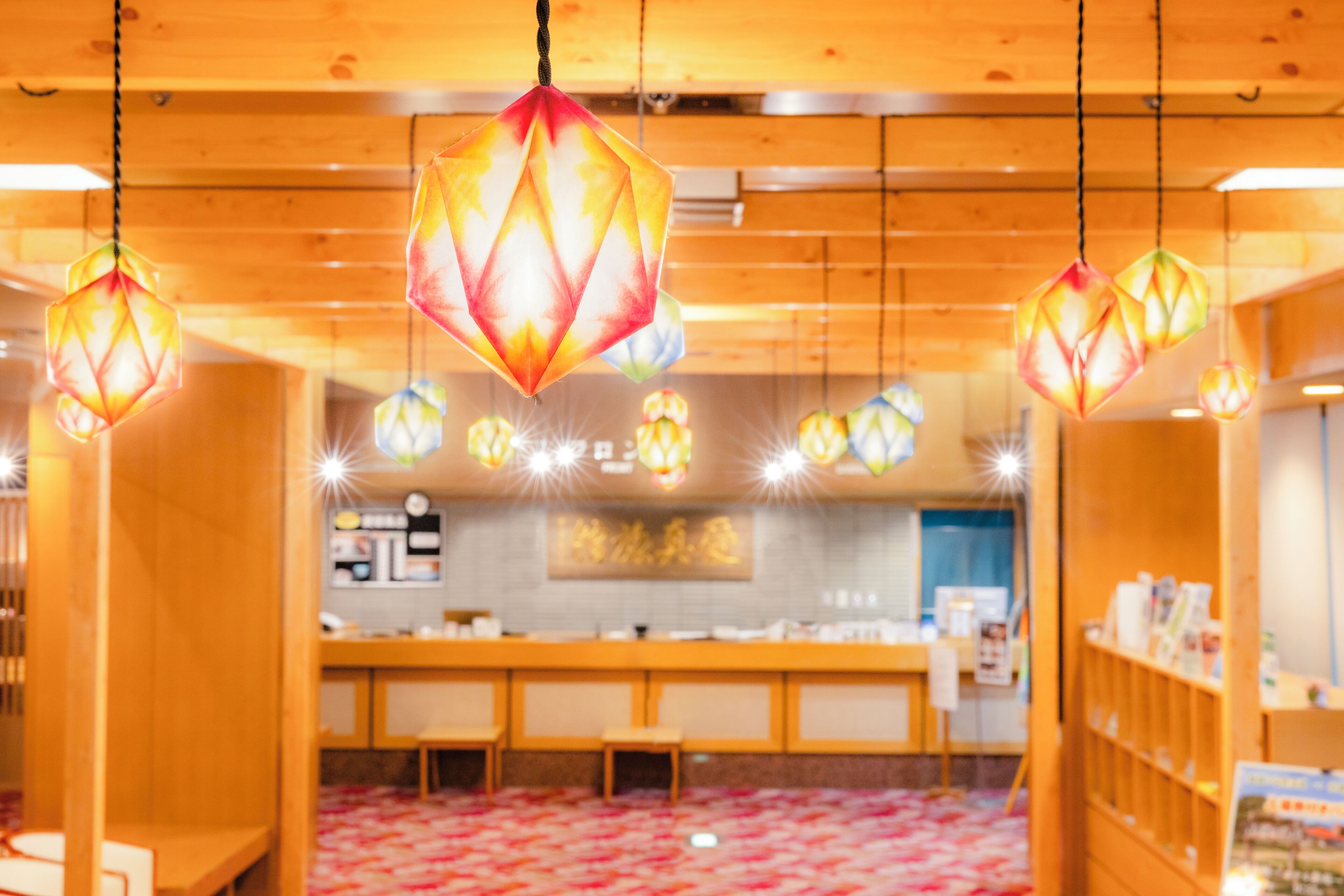 Een restaurant interieur met hangende zeshoekige lampen, houten meubels en een betegelde vloer.