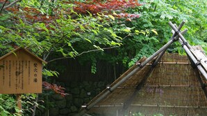 A traditional Japanese onsen with a stone bath, bamboo structures, and a signboard. - Aishinkan (Morioka)