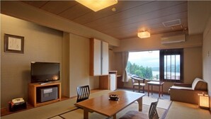 A traditional Japanese-style room with tatami flooring, a television, a dining table, and a sofa. - Aishinkan (Morioka)