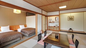 A traditional Japanese-style hotel room with tatami flooring, a low table, and a futon bed. - Aishinkan (Morioka)