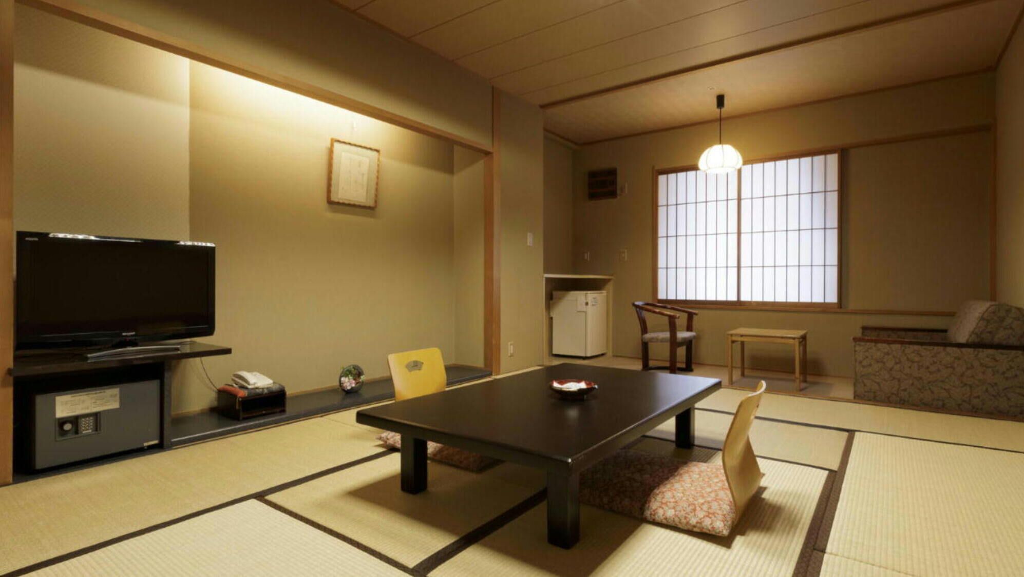 A traditional Japanese-style room with tatami flooring, a television, a refrigerator, and a sofa.