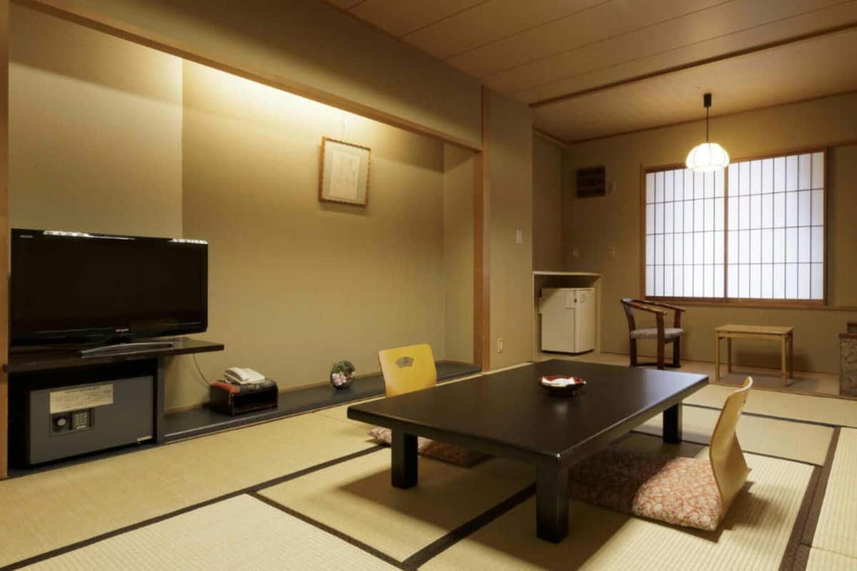 Une pièce de style japonais traditionnel, avec un sol recouvert de tatamis, une télévision, un réfrigérateur et un canapé.