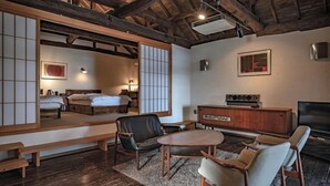 A traditional Japanese-style room with tatami flooring, a low wooden bed, a television, and a radio. - Izukogen Onsen Hananokumo (Ito)