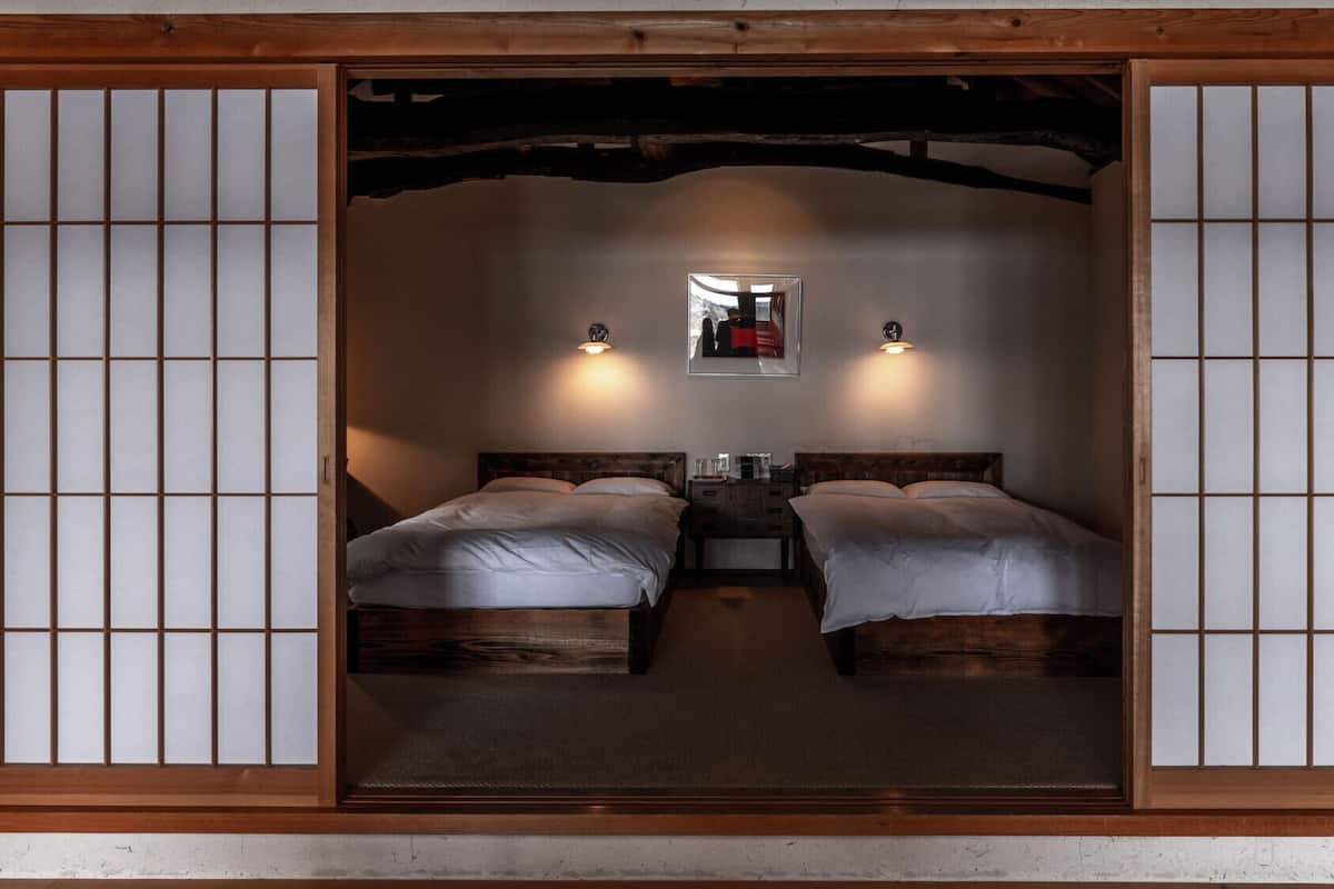 Ein traditionell gestalteter japanischer Raum mit zwei Betten, einem Spiegel und zwei Wandleuchten.