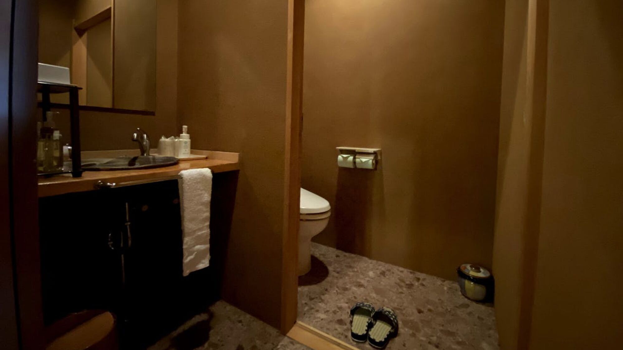 A small bathroom with a sink, toilet, and a towel hanging on the wall.