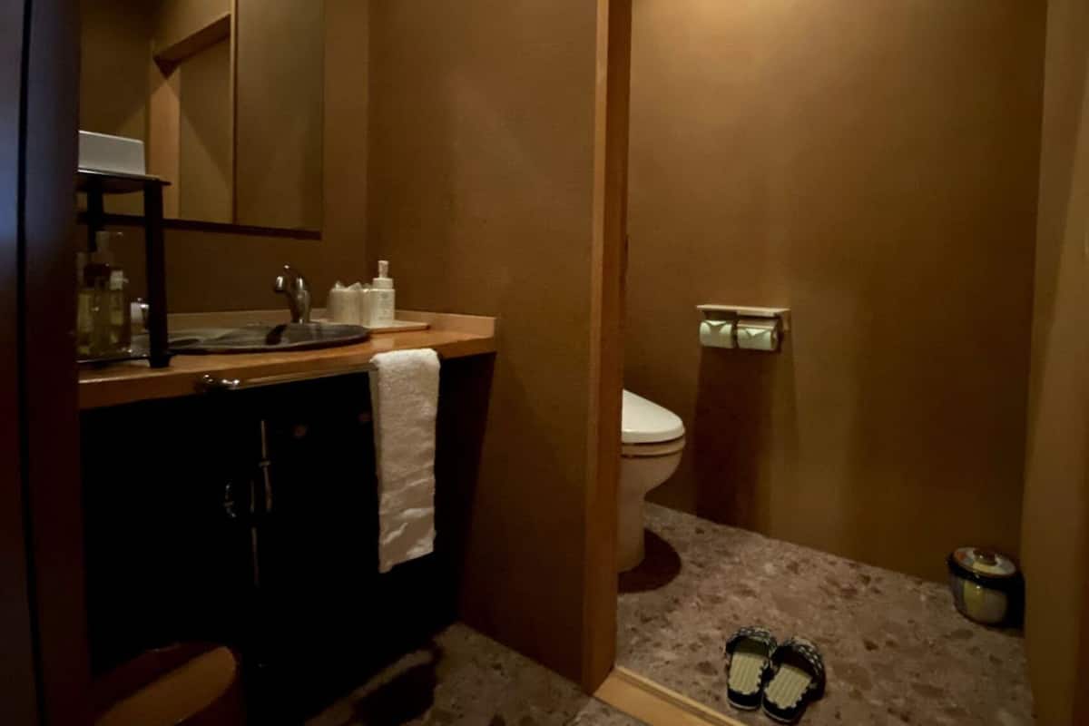 Ein kleines Badezimmer mit Waschbecken, Toilette und einem Handtuch, das an der Wand hängt.