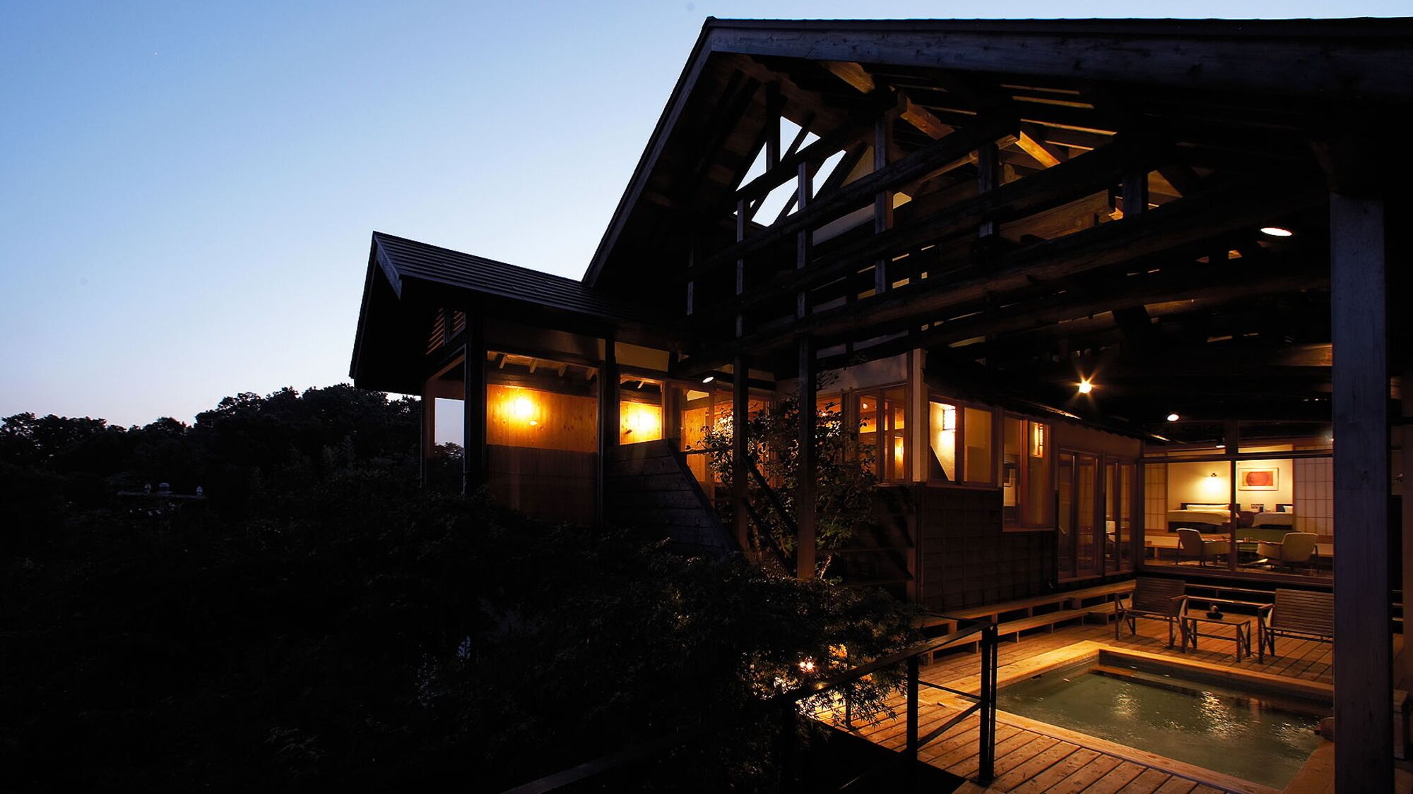 A modern building with a wooden deck, a hot tub, and a dining area.