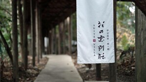 A pathway lined with wooden posts and a white banner with Japanese text. - Izukogen Onsen Hananokumo (Ito)