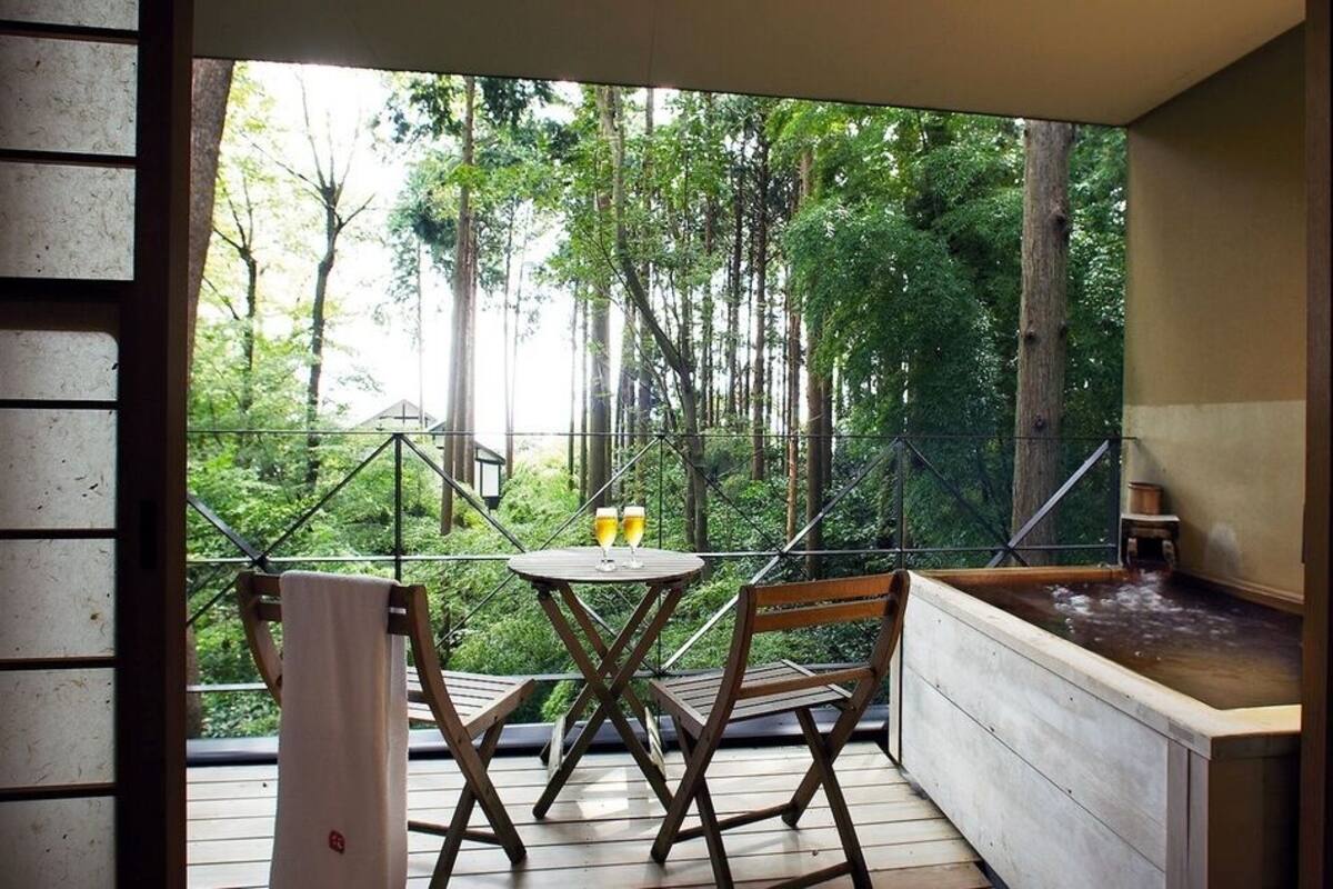 Ein Balkon mit Tisch und Stühlen, einem Whirlpool und Blick auf einen Wald.