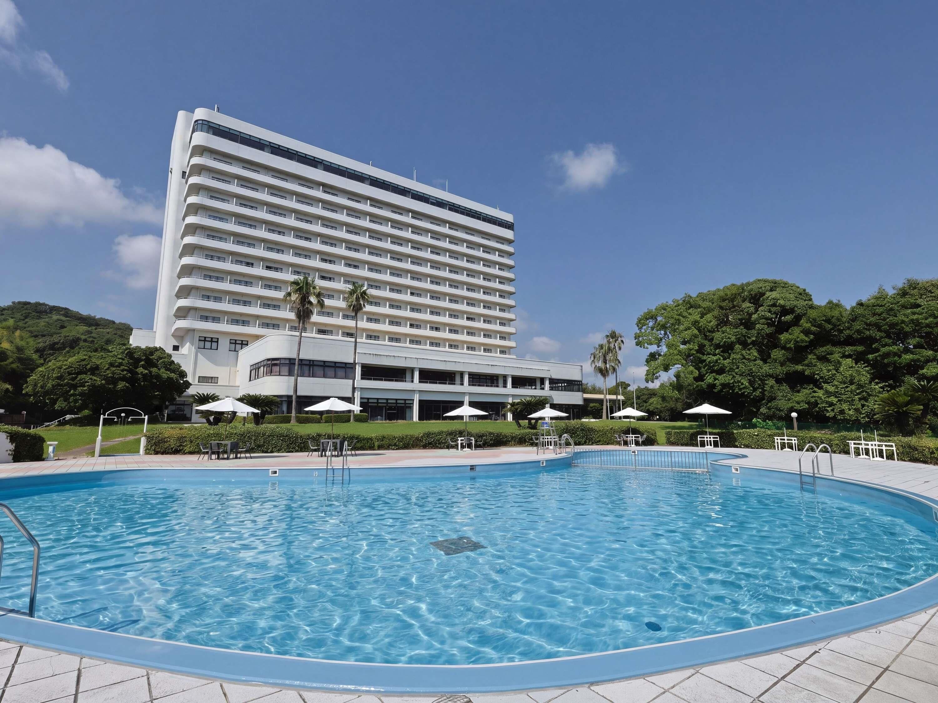Un hotel con piscina, palme e un cielo azzurro limpido.