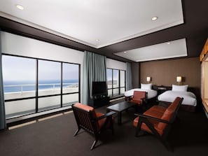 A hotel room with a large window, a flat-screen TV, a bed, a desk, and two chairs. - Mercure Kochi Tosa Resort & Spa (Geisei)
