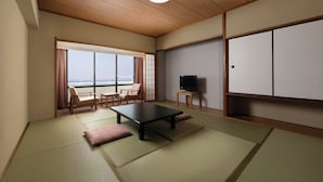 Una habitación tradicional japonesa con suelo de tatami, una mesa baja, un televisor y una puerta corredera que da a un balcón con vistas.