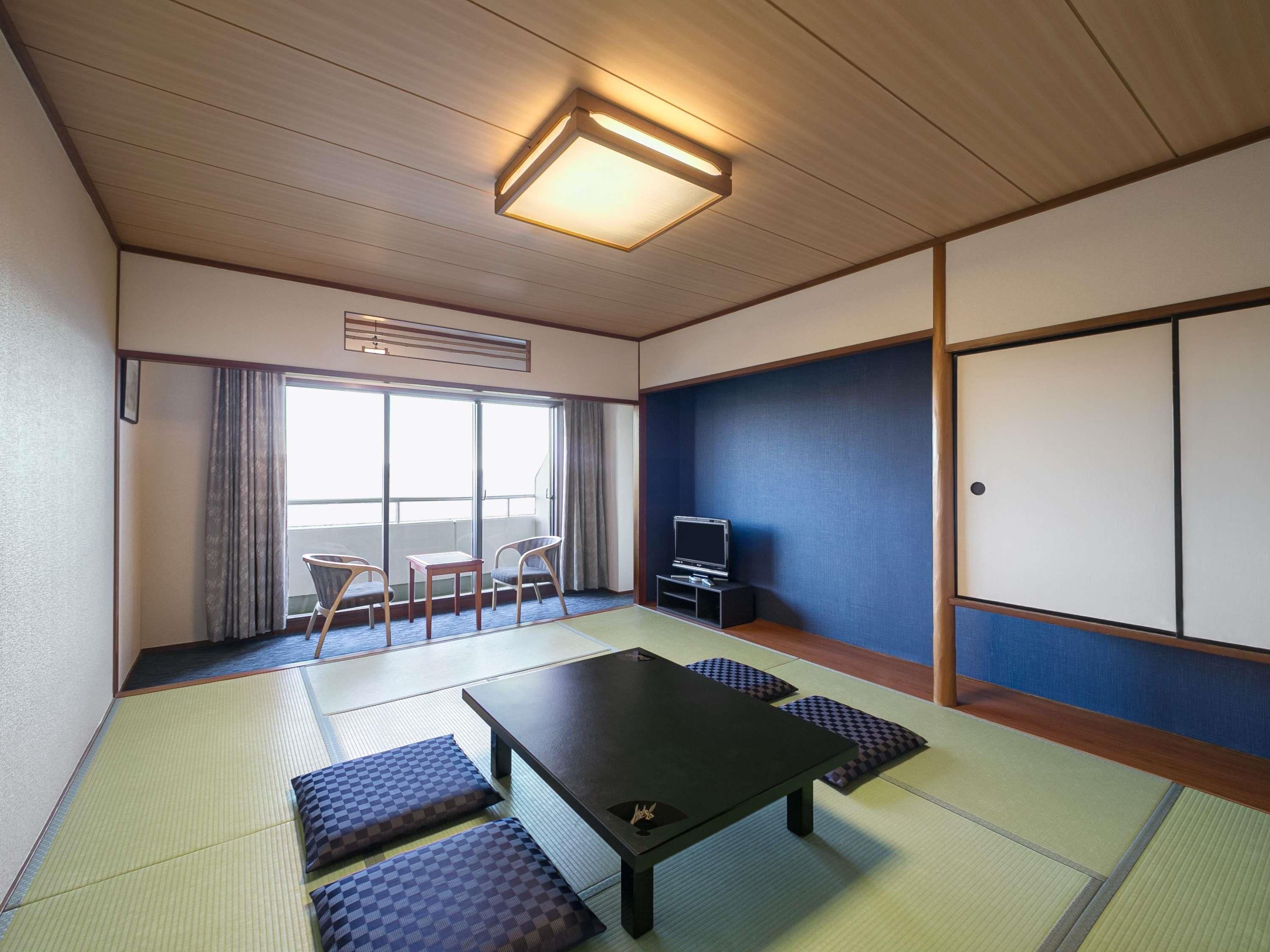 A traditional Japanese room with tatami flooring, a low table, a television, and a sliding door.