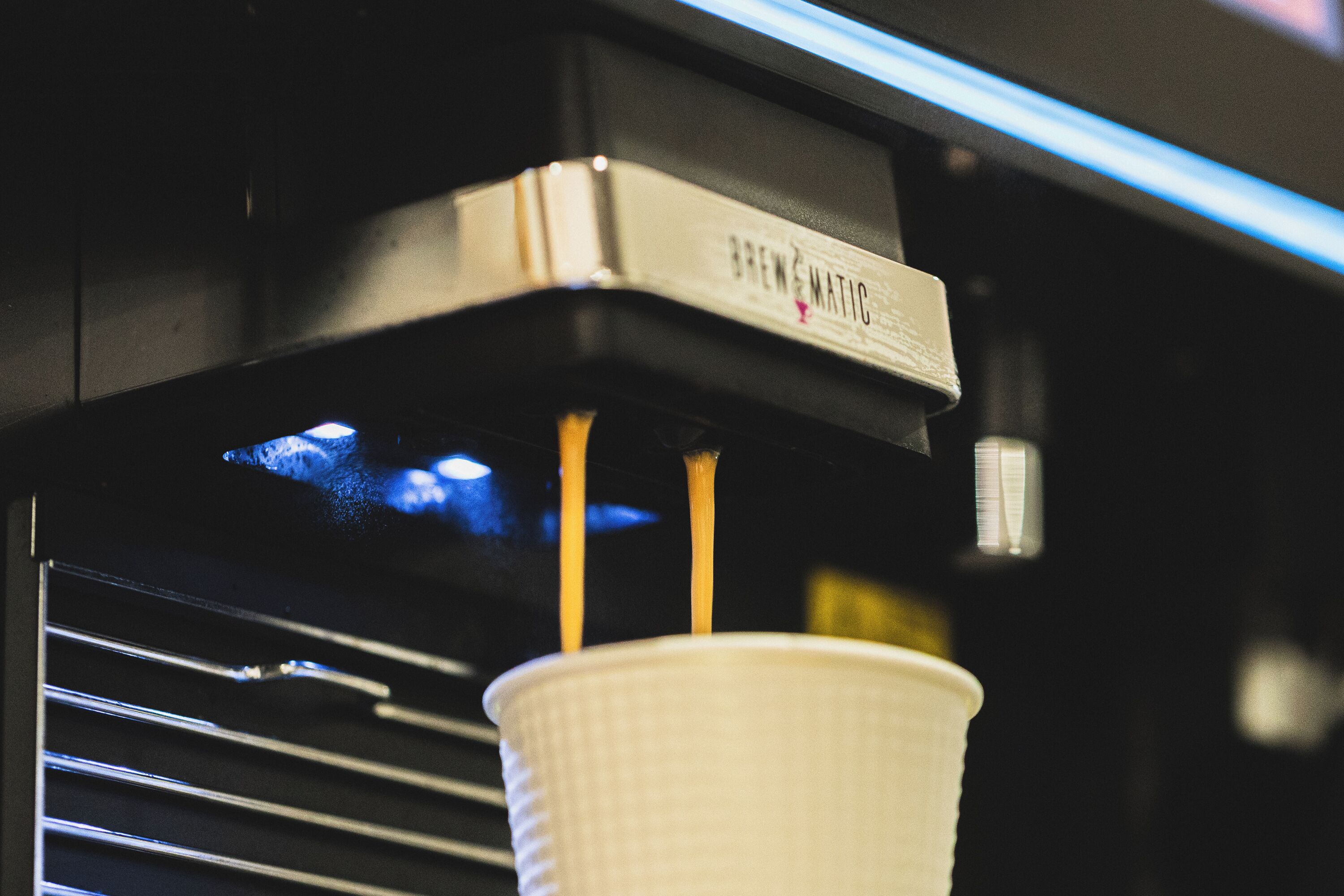 Una cafetera sirviendo café en un vaso de papel.