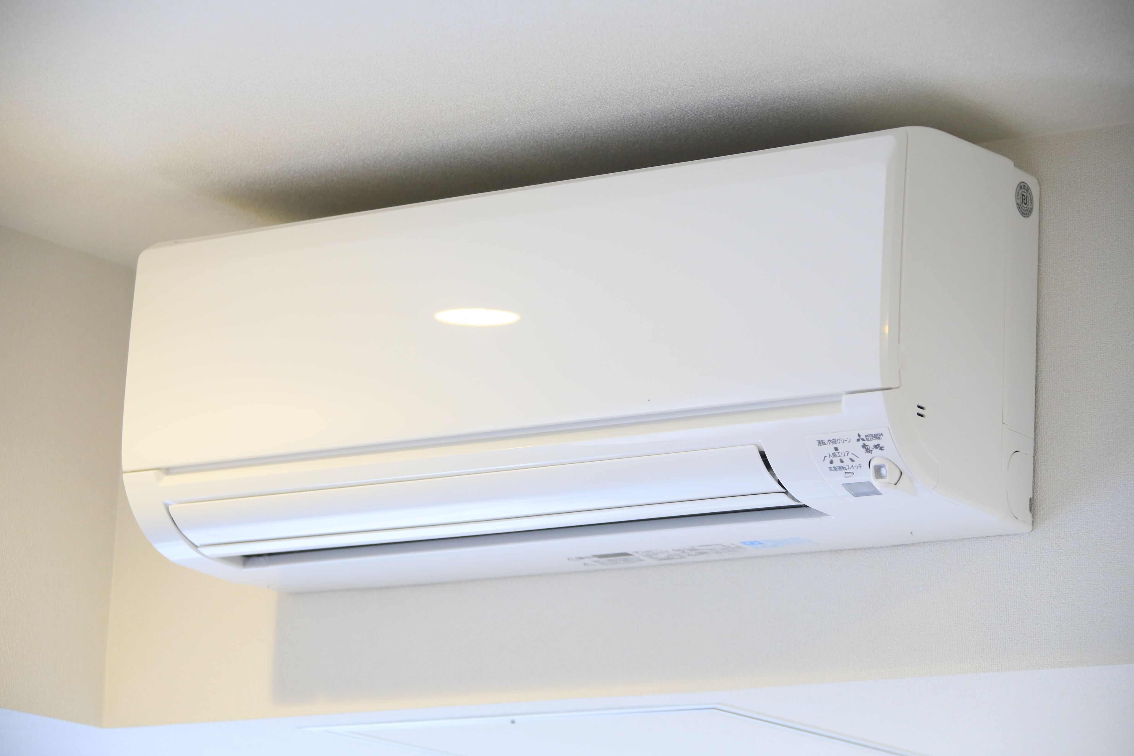 A white wall-mounted air conditioning unit with a control panel and a small vent.