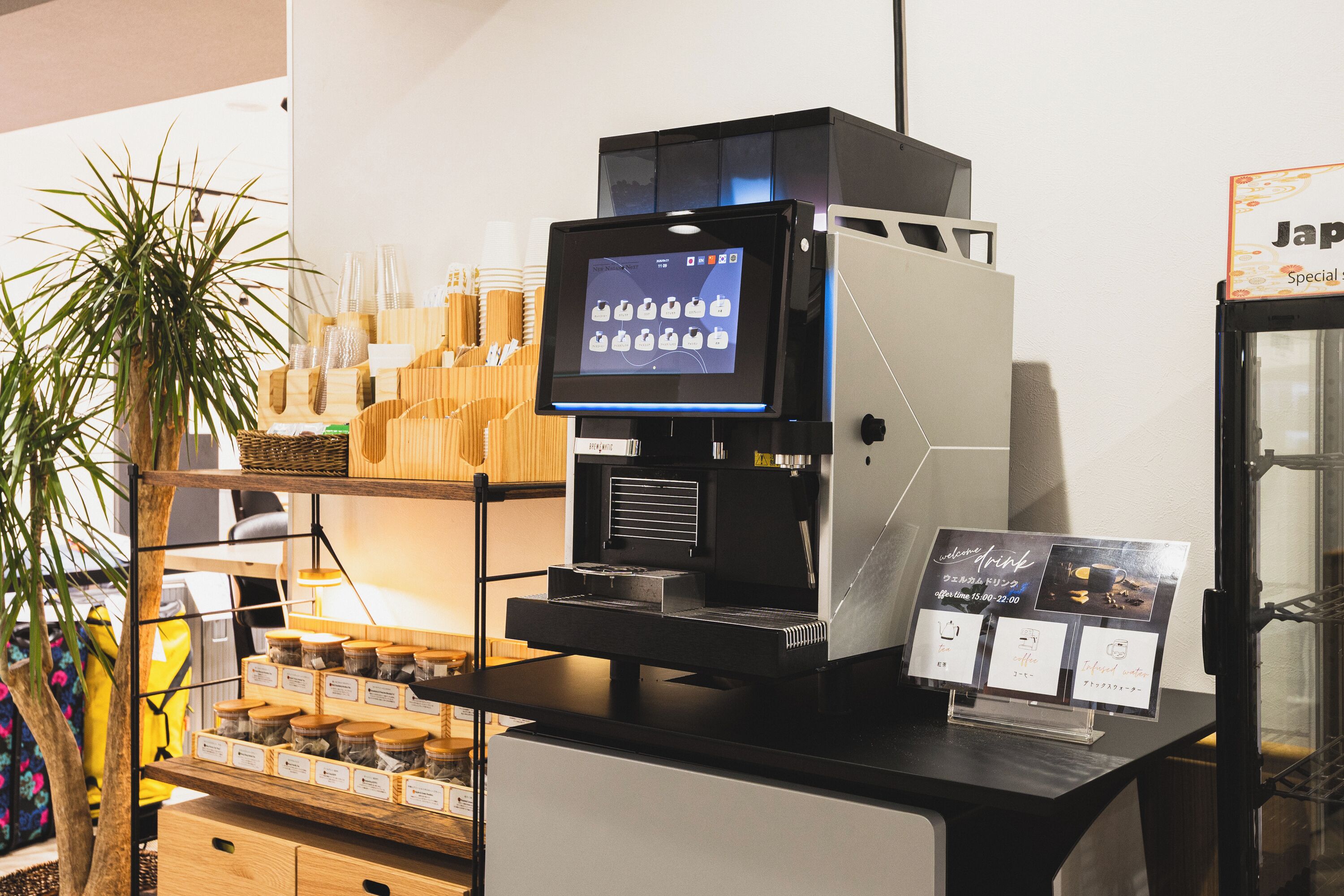 A coffee machine with a digital display, a menu board, and a shelf with jars of condiments.