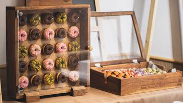 Uma vitrine de madeira com donuts variados e uma caixa de madeira com uma placa que diz 'New Nagano Next Hotel'.