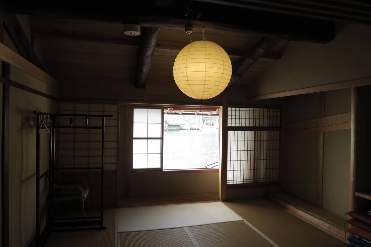 A traditional Japanese room with tatami flooring, sliding doors, and a hanging paper lantern.