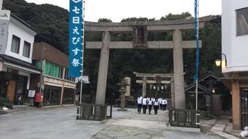 Un portail torii japonais traditionnel, typique des sanctuaires, se dresse à l’entrée, avec un chemin de pierre menant jusqu’à lui.