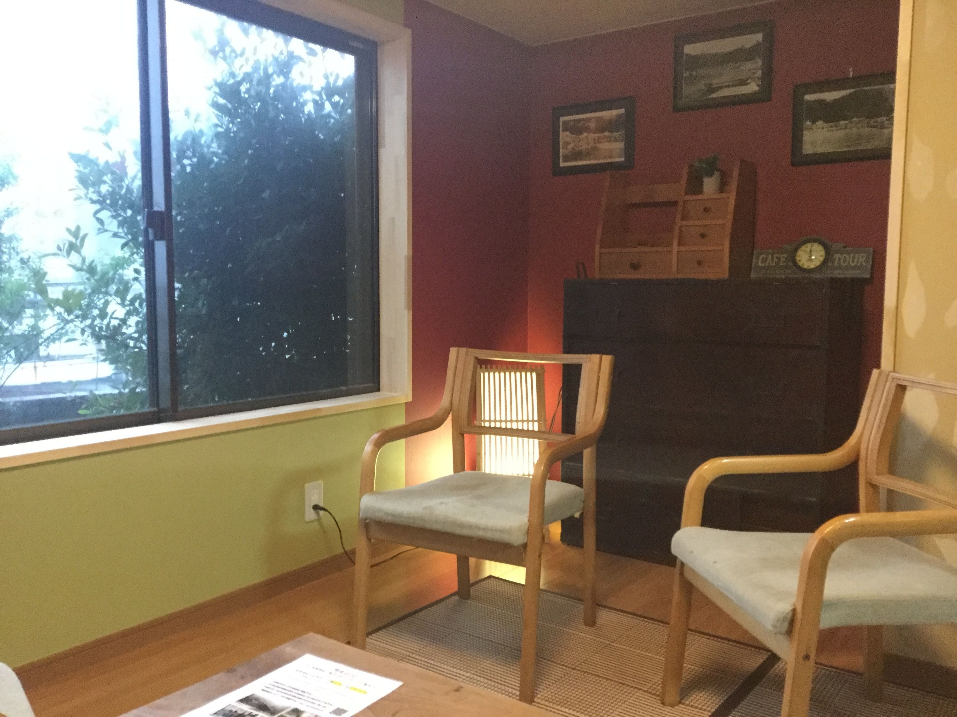 A room with two wooden chairs, a fireplace, and framed pictures on the wall.