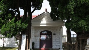 Un edificio blanco con techo rojo, una entrada central con un arco decorativo y un cartel.