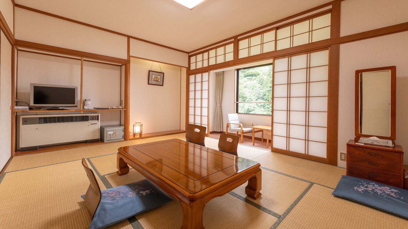 A traditional Japanese room with tatami flooring, a wooden table, chairs, a television, and sliding doors.