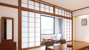 A traditional Japanese-style room with tatami flooring, a low table with chairs, a television, and a heater. - Yuzawa Toei Hotel (Yuzawa)