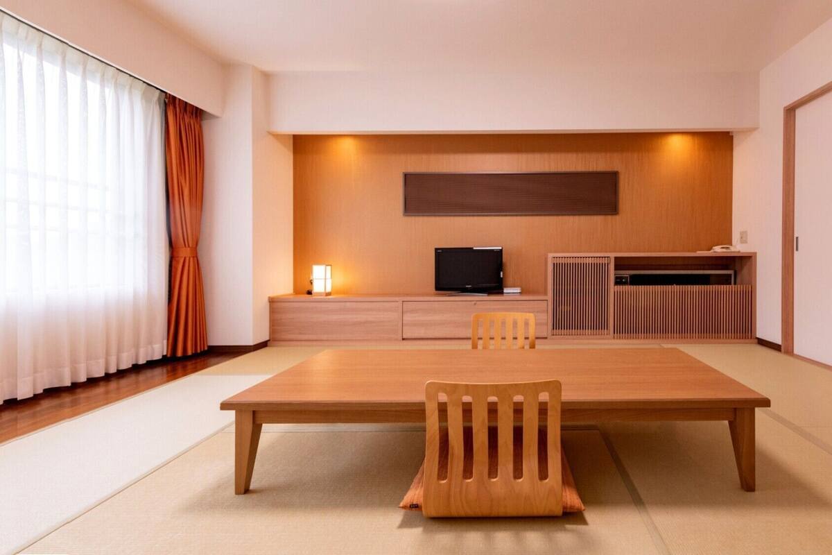 A modern room with a wooden dining table, chairs, a TV, and a cabinet.