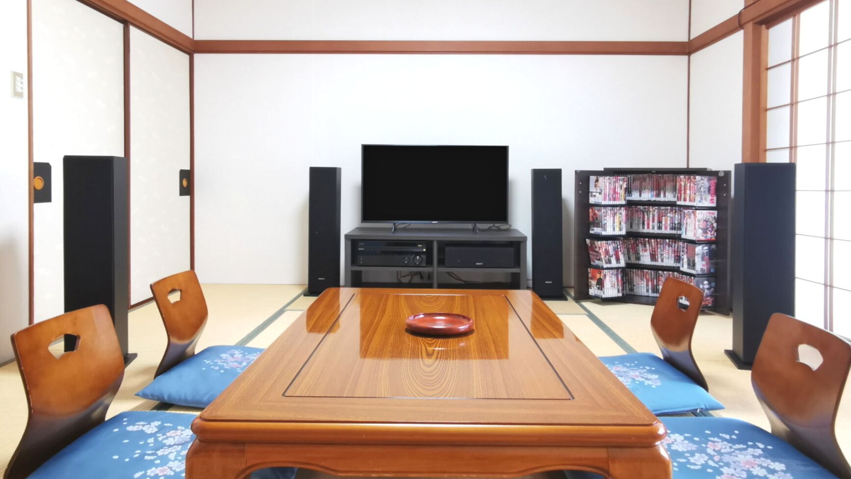 A traditional Japanese-style room with tatami flooring, a low wooden table, and a television.