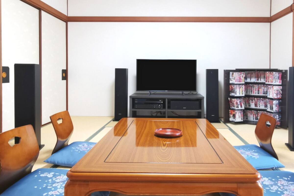 A traditional Japanese-style room with tatami flooring, a low wooden table, and a television.