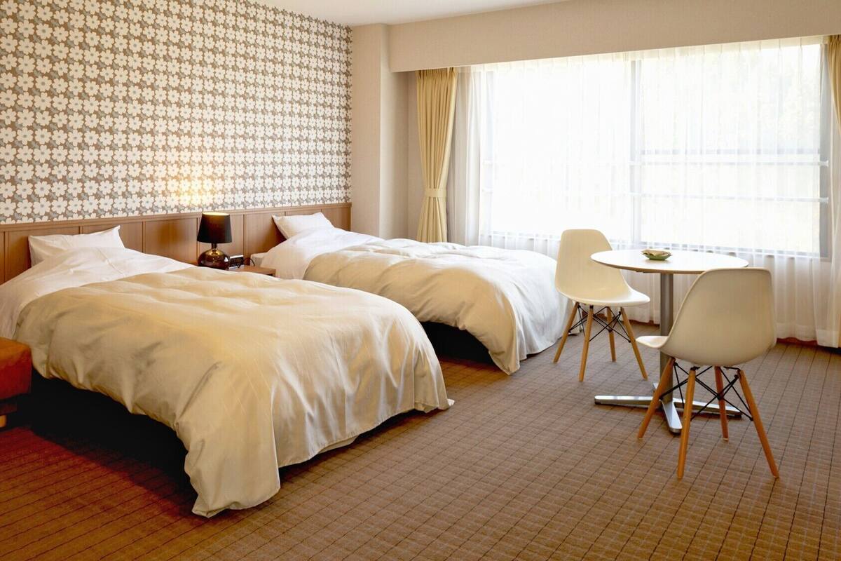 A hotel room with two beds, a sofa, a table, and chairs.