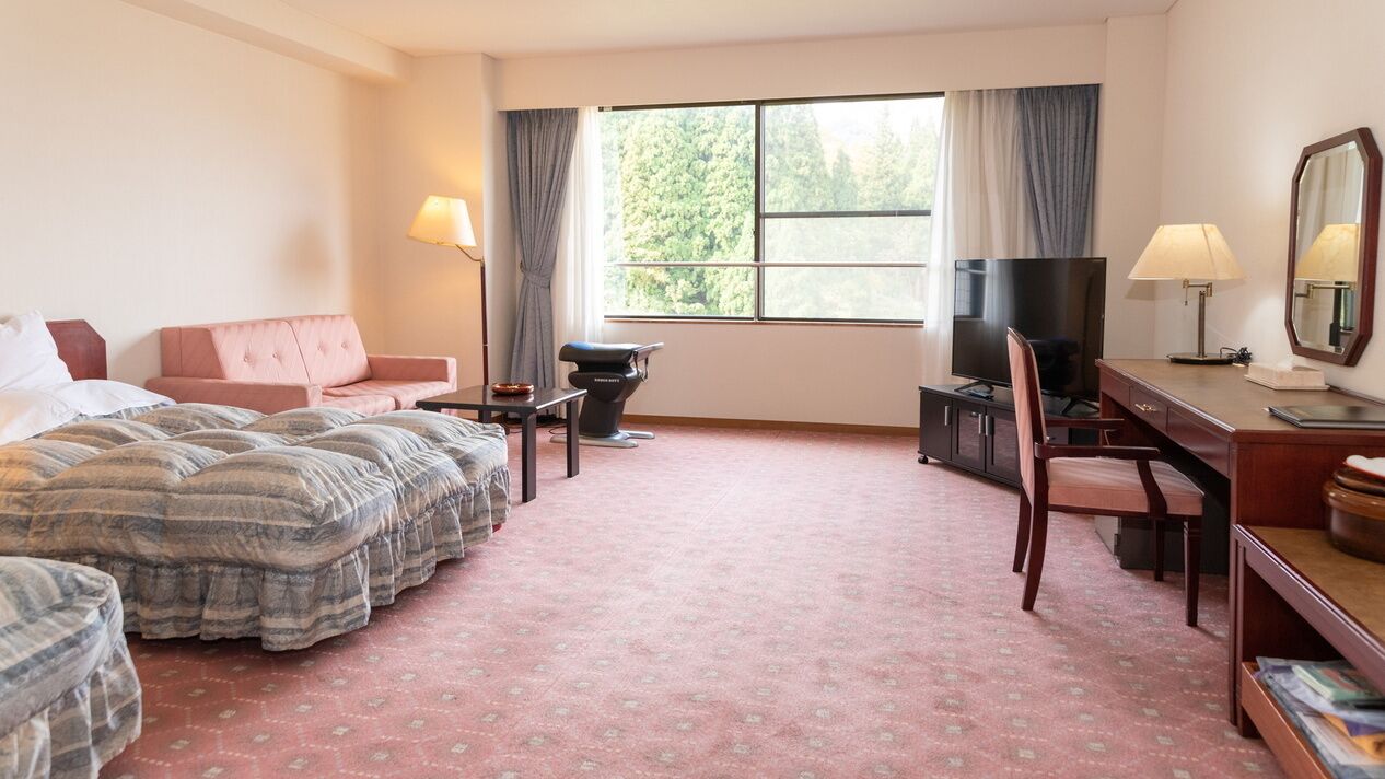 A hotel room with a bed, a desk, a chair, a television, and a window with curtains.