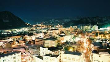 A nighttime cityscape with buildings, roads, and mountains in the background.