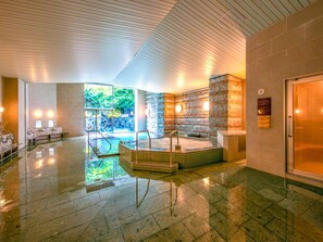 Un área de spa con un jacuzzi, una pared de piedra y una puerta de vidrio.