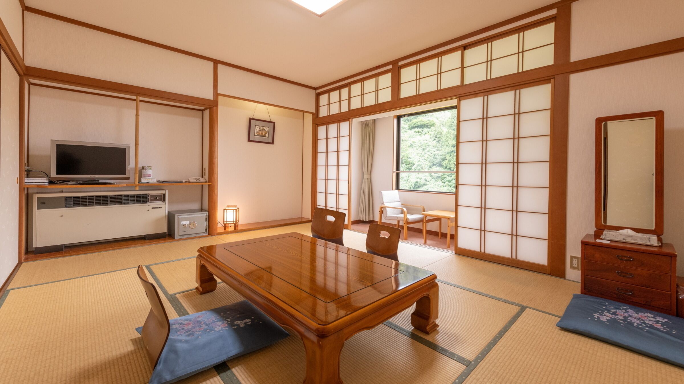 Habitació japonesa tradicional amb sòl de tatami, una taula de fusta, televisió i una porta corredissa que dóna a un balcó.