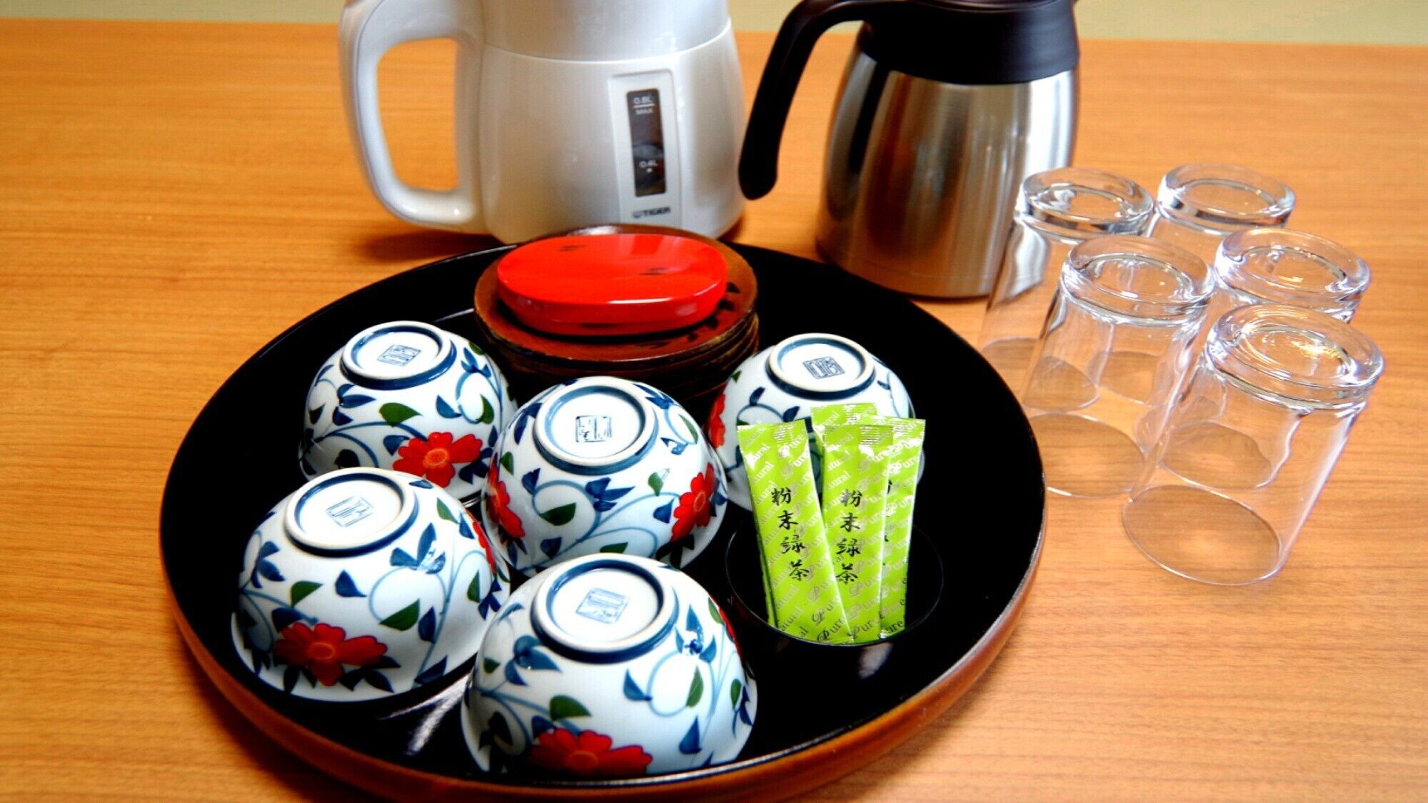Plat amb tasses de te, una teiera i bosses de te sobre una taula de fusta.