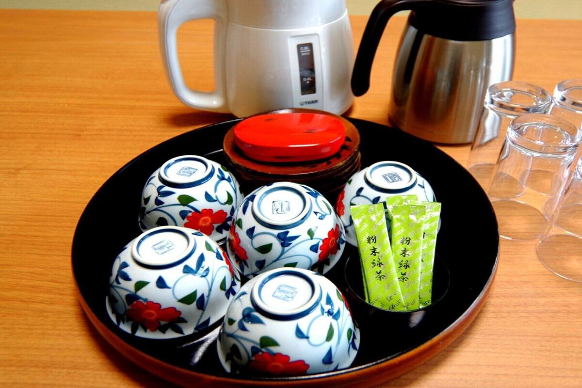 A plate with teacups, a teapot, and tea bags on a wooden table.