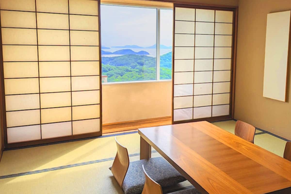 A traditional Japanese room with tatami flooring, a wooden table, and shoji screens.
