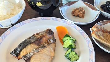 A table with various dishes including fish, cucumber slices, and a bowl of rice.