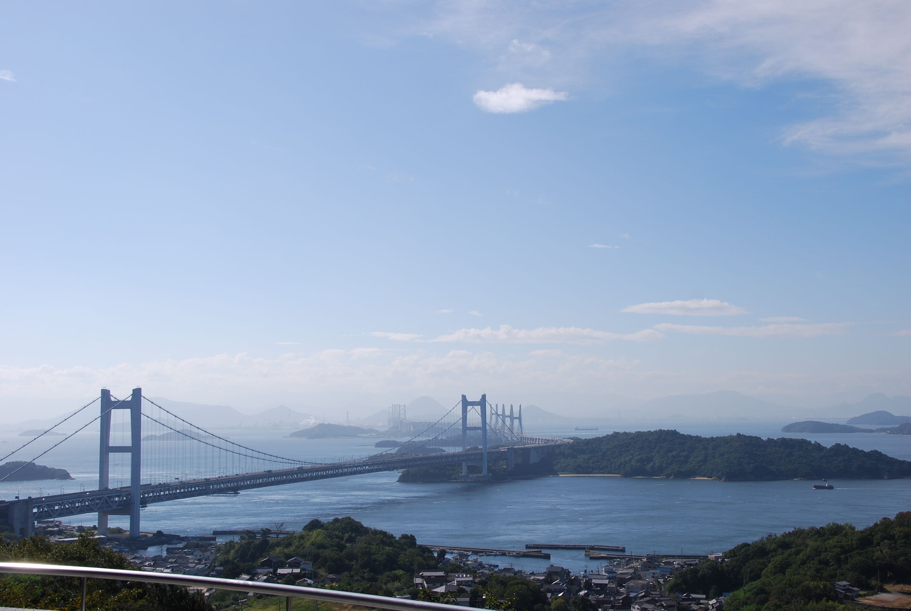 Un grand pont suspendu enjambant une étendue d’eau, avec une vue sur la ville en arrière-plan.