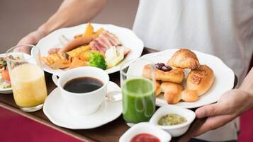 A tray with breakfast items including croissants, a green drink, and a plate with eggs and bacon.