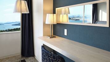 Habitación de hotel con vistas a un puente y al agua, una consola de madera, dos lámparas, un espejo y una silla estampada.
