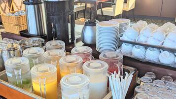 A buffet setup with various food and drink containers, including jars of sauces and a coffee station.