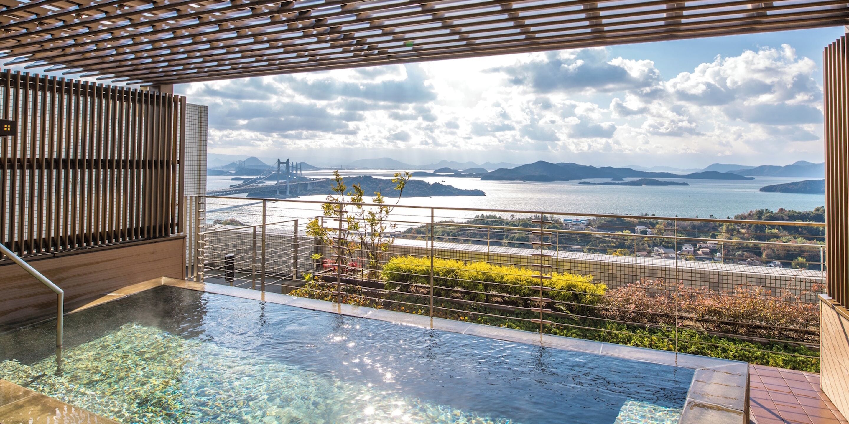An infinity pool with a view of a bridge and mountains.