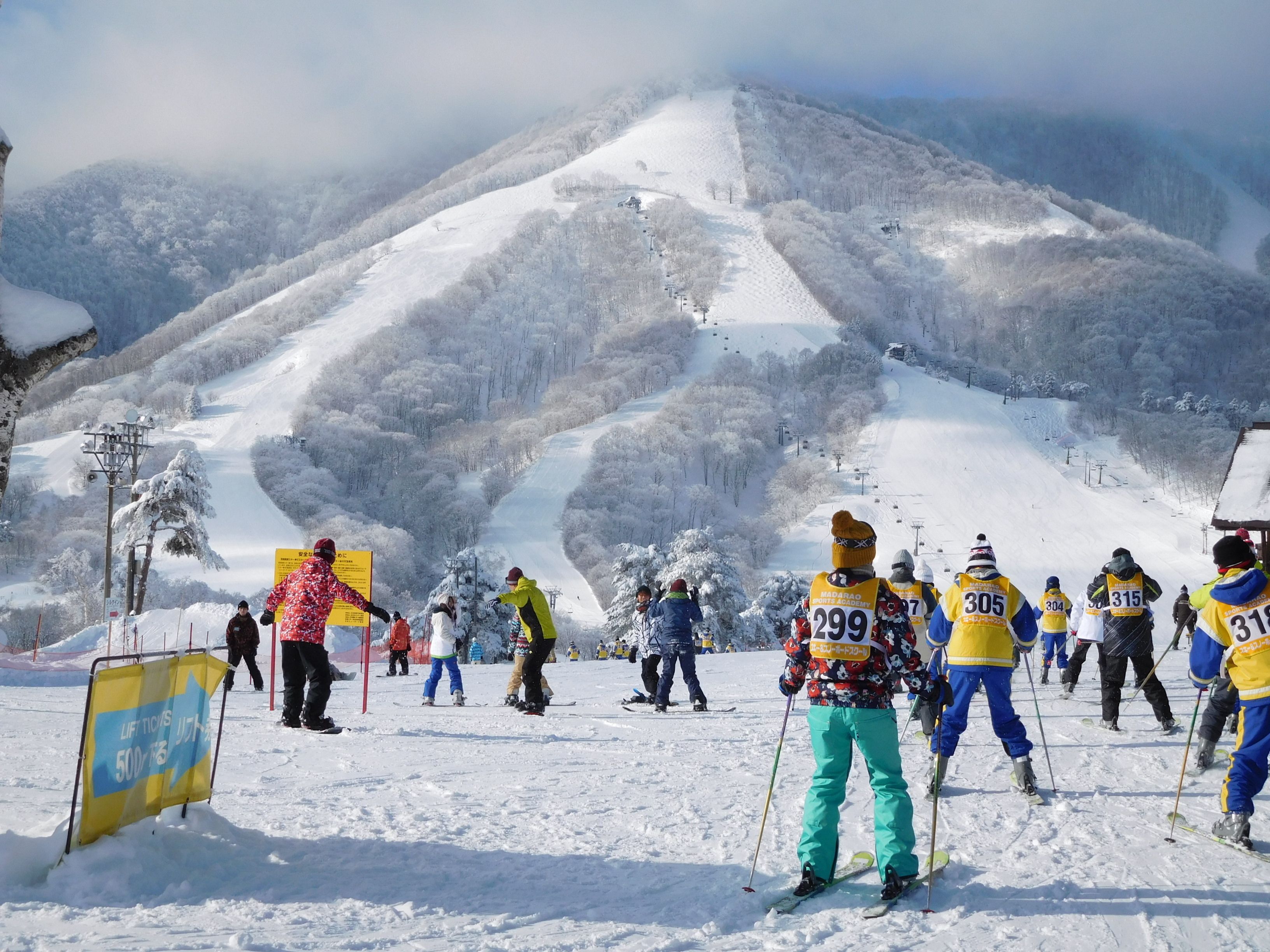 Une piste de ski avec des skieurs et un panneau indiquant le prix des forfaits.