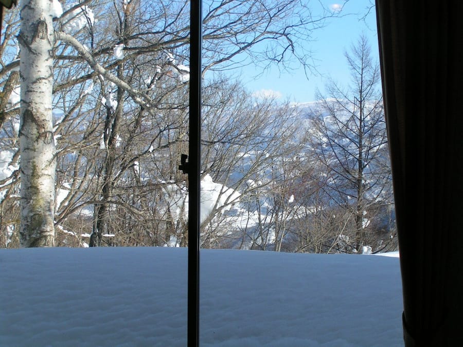A snowy landscape with bare trees and a clear sky.