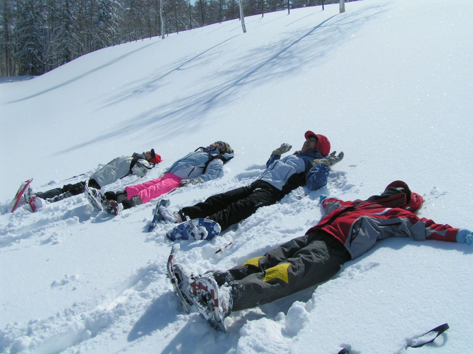 A group of people lying on a snowy slope, wearing winter sports gear.