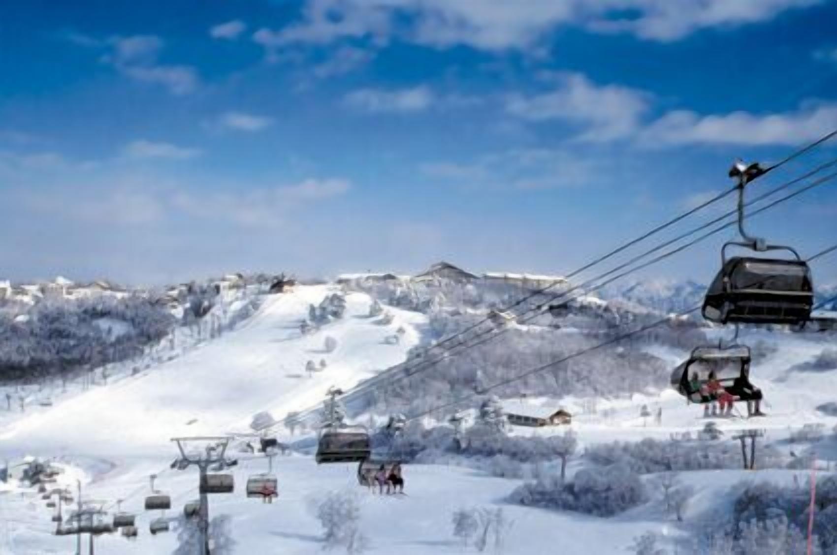 A ski lift with chairs ascending a snowy mountain slope.